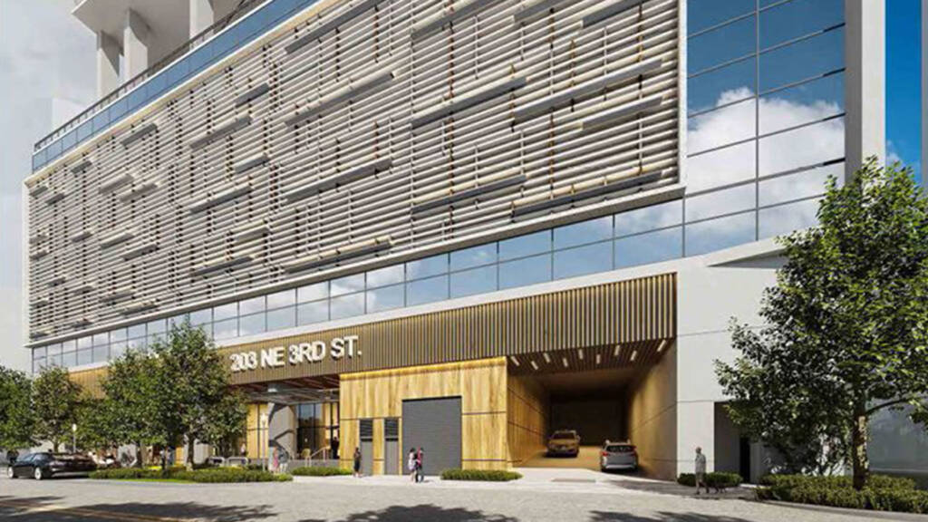 A street-level architectural rendering of the North Tower at 203 NE 3rd St in Fort Lauderdale, FL. The image showcases a modern podium with vertical wood slats, stone cladding, and a multi-story glass facade. A large covered entrance serves as a vehicular gateway, while pedestrians are shown on the sidewalk in front of ground-floor retail spaces under a clear blue sky.